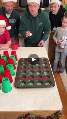 a group of people standing around a table with cupcakes in front of them