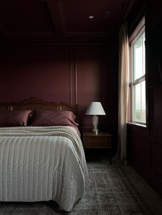 a bed sitting in a bedroom next to a window with a lamp on top of it