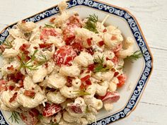 a white plate topped with pasta salad on top of a blue and white table cloth