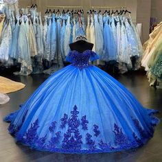 a blue ball gown is on display in a dress shop with other dresses behind it