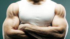 a man with his arms crossed wearing a white tank top