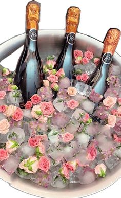 three bottles of champagne in ice with pink flowers