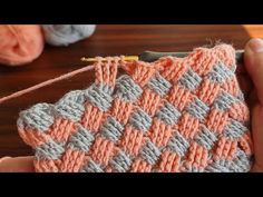 someone is holding an orange and gray crochet piece with yarn in the background