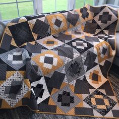 a black and yellow quilt sitting on top of a couch next to a large window