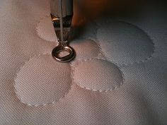 a close up of a sewing machine stitching something on a piece of white fabric