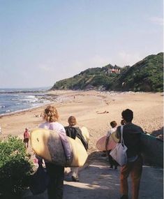 several people carrying surfboards down a path to the beach