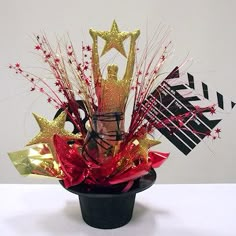 a black vase filled with lots of red and gold decorations on top of a white table