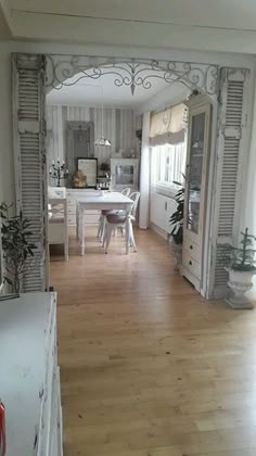 an open kitchen and dining room area with wood flooring, white painted walls and wooden floors