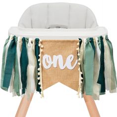 a baby's highchair with the word one on it and tassels