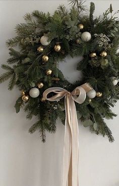 a christmas wreath hanging on the wall with gold and white ornaments around it's edges