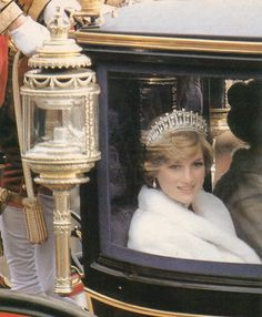 the princess is wearing a tiara while riding in a horse drawn carriage down the street