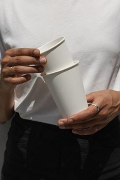 a person holding a white cup in their hands