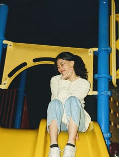 a woman sitting on top of a yellow slide