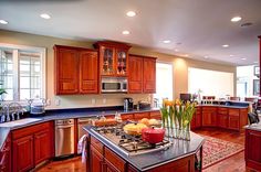 a large kitchen with wooden cabinets and stainless steel appliances, along with an island in the middle