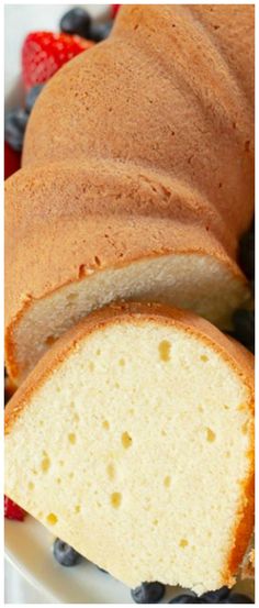 a loaf of pound cake sitting on top of a white plate with blueberries and strawberries