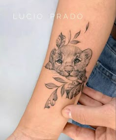 a woman's arm with a small tattoo of a lion and leaves on it