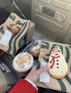 someone is holding up some cookies in the car with frosting on them and snowmen