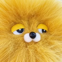 a close up of a stuffed animal with yellow fur on it's face and eyes