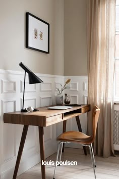 a wooden desk with a lamp on top of it next to a chair and window