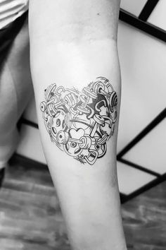 a black and white photo of a heart shaped tattoo on the right arm, with many faces drawn in it