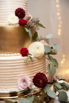 a wedding cake with flowers and greenery on top