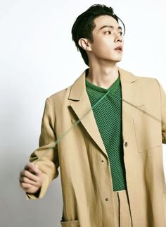 a young man wearing a tan coat and green shirt