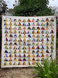 a large quilt is hanging on the side of a building with trees in the background