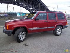 a red jeep is parked under a bridge