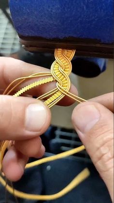 the person is working on something with gold colored thread and metal wire in their hands