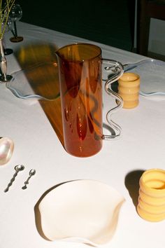 the table is set with dishes and utensils on it, including a glass vase