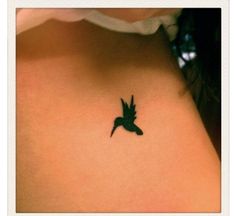 a small bird tattoo on the back of a woman's left side ribcage