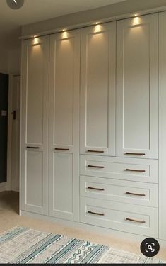 a large white closet with drawers and lights on the wall next to carpeted floor