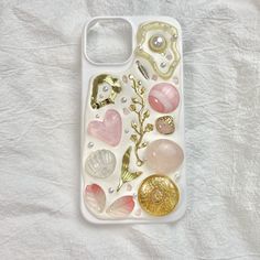 a cell phone case with many different types of buttons and charms on the back, sitting on a white sheet