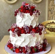 a three tiered cake decorated with berries and flowers