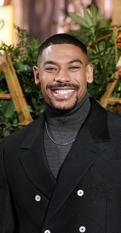 a man in a black suit smiling at the camera