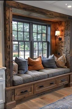 a window seat in the corner of a living room with lots of pillows on it