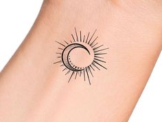 the sun and moon tattoo is shown on someone's left arm, with black ink