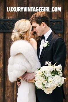 a bride and groom standing next to each other in front of a wooden door with flowers