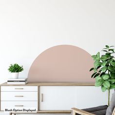 a living room with a plant in the corner and a white wall behind it that has a pink circle painted on it