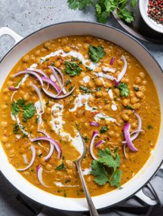 a white bowl filled with chickpea and red onion soup, garnished with cilantro