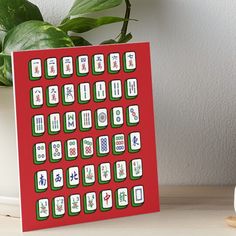 a red card with white and green symbols on it next to a potted plant