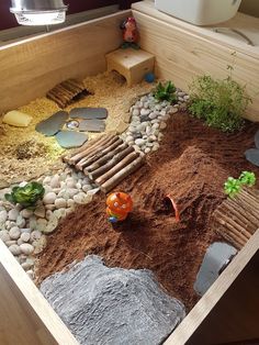 a wooden box filled with lots of dirt and rocks next to a small garden area