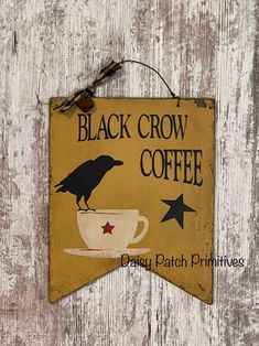 a black crow coffee sign hanging on the side of a wooden wall with stars and a cup