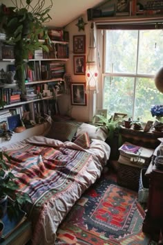 a bed sitting under a window in a bedroom next to a book shelf filled with books