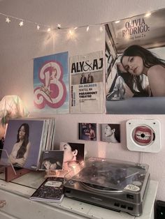 there is a record player on top of a dresser in this room with pictures and lights