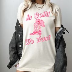 We love how our "In Dolly We Trust" Dolly Parton graphic tee turned out!  The perfect gift for any Dolly Parton fan or music lover!  The girly cowgirl design is right on trend.  Printed on super soft, ultra high quality Bella & Canvas Tee.   **All designs are printed direct to garment ensuring the highest quality of color, design, and longevity. Printed in our print shop located in Cleveland, Ohio. We are able to provide our customers lighting fast shipping and the ability to alter any image/des Dolly Parton Graphic, Girly Cowgirl, In Dolly We Trust, Dolly Parton Shirt, Cowgirl Shirts, Coastal Cowgirl, Cow Girl, Bella Canvas Tees, Cleveland Ohio