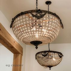 two chandeliers hanging from the ceiling in a room with white walls and wood trimming