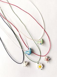 A beautiful and classic necklace for all stylish women and girls. Ceramic pendants on cotton thread 120 cm. Thread colors: black, grey, red,beige or green.  + furniture 14k gold plated and pearls\ natural stones. Size : -bird 1,5-2 cm x 1,5 cm - red flower 1,5 cm x 1-1,2 cm - chamomile 1,5 x1,5 cm  Other necklace https://www.etsy.com/de-en/shop/kontoorstitch?ref=shop-header-name&listing_id=1739012541&from_page=listing&section_id=42566702 Cute Beaded Necklaces For Summer Gifts, Cute Necklaces For Spring Gift, Cute Spring Necklace As A Gift, Cute Spring Necklace For Gift, Cute Spring Gift Necklaces, Spring Gift Adjustable Beaded Necklace, Adjustable Beaded Necklace For Spring Gift, Heart-shaped Summer Necklaces Perfect As Gifts, Handmade Necklaces For Summer Gifts