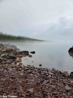 the water is very calm and there are rocks on the shore