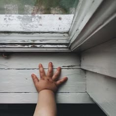 a child's hand reaching out the window sill